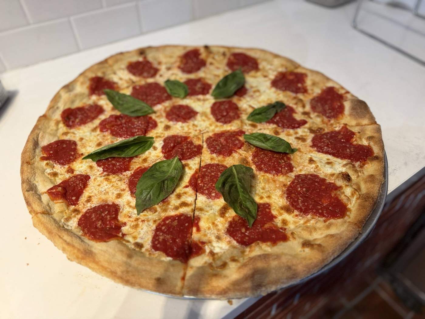 A whole pepperoni pie with basil leaves on top