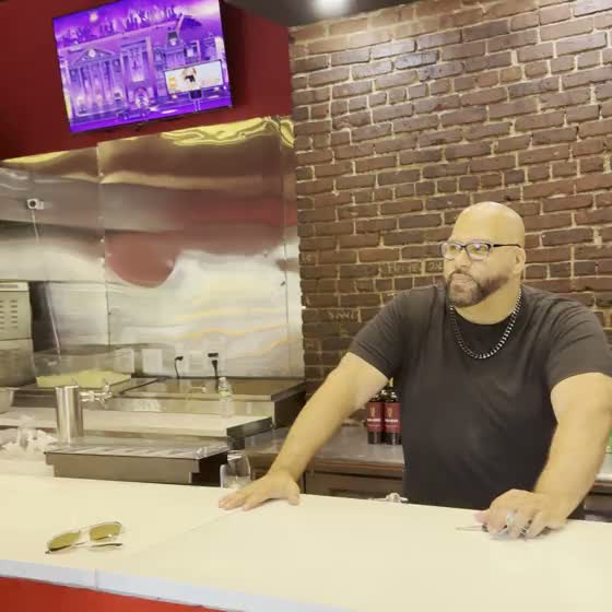 Inside Ray's Corner: the lit chrome sign, red walls, the pizza case