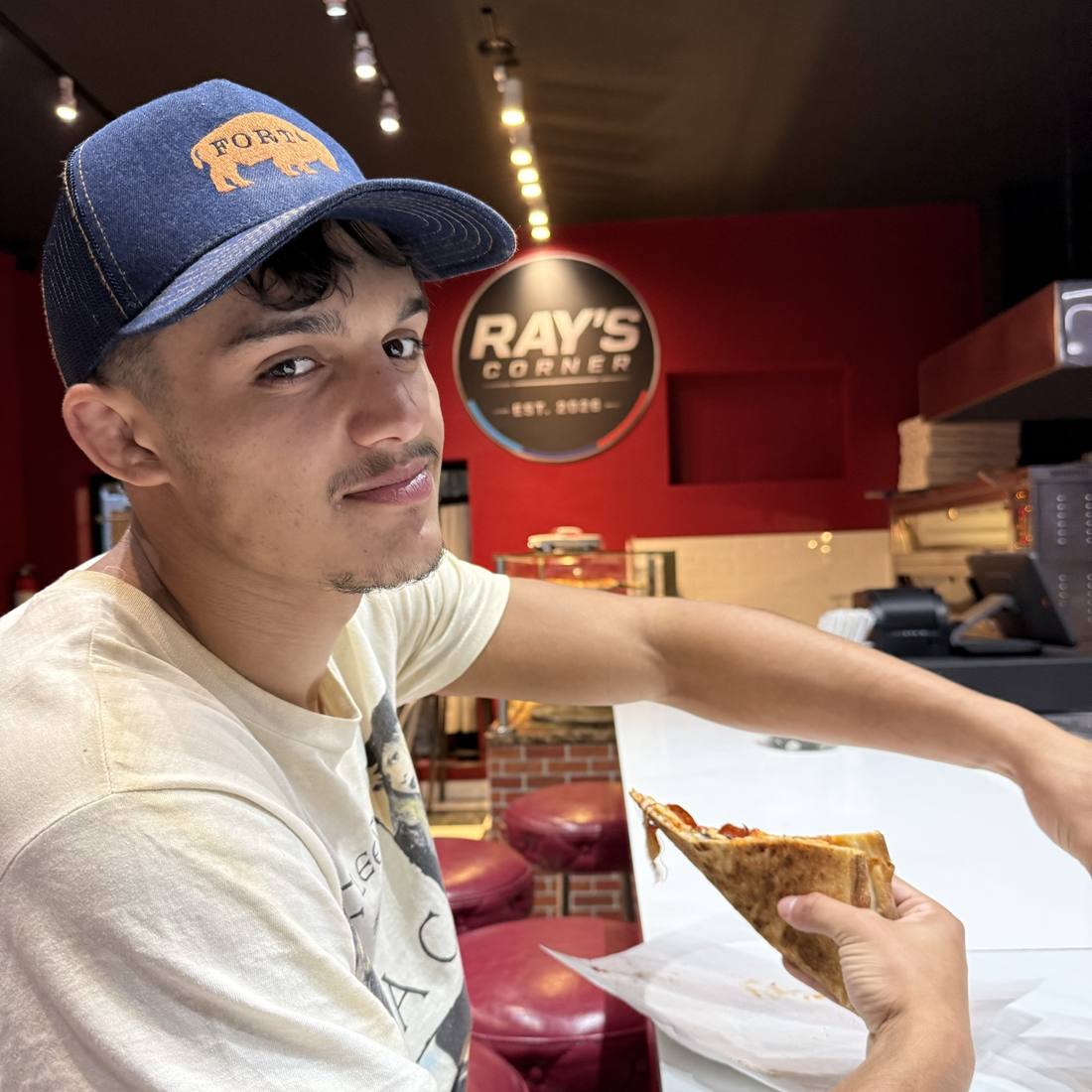 A customer with a slice at the counter